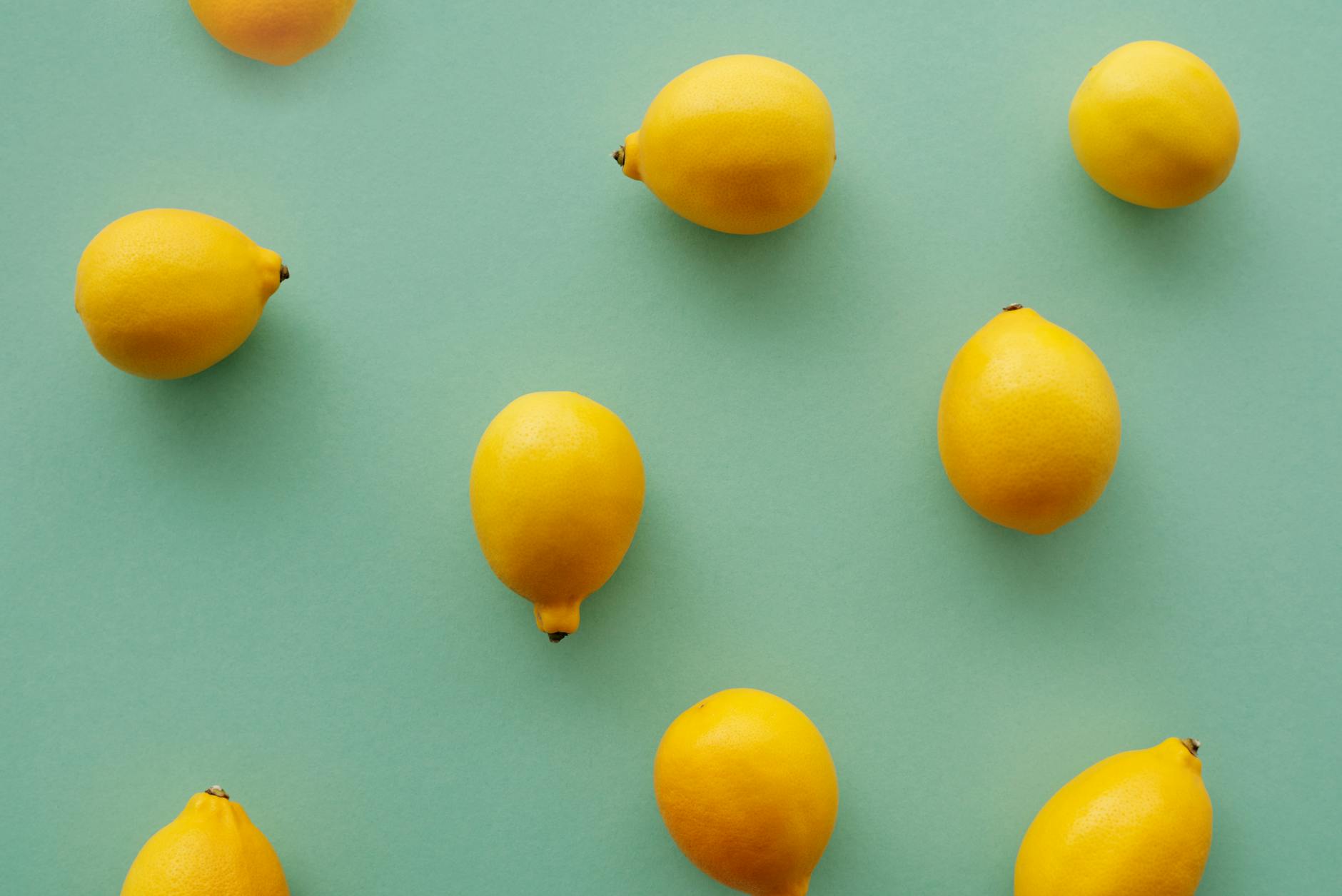 Bright yellow lemons arranged on a pastel green background, representing fresh approaches to intimate wellness during hormonal shifts