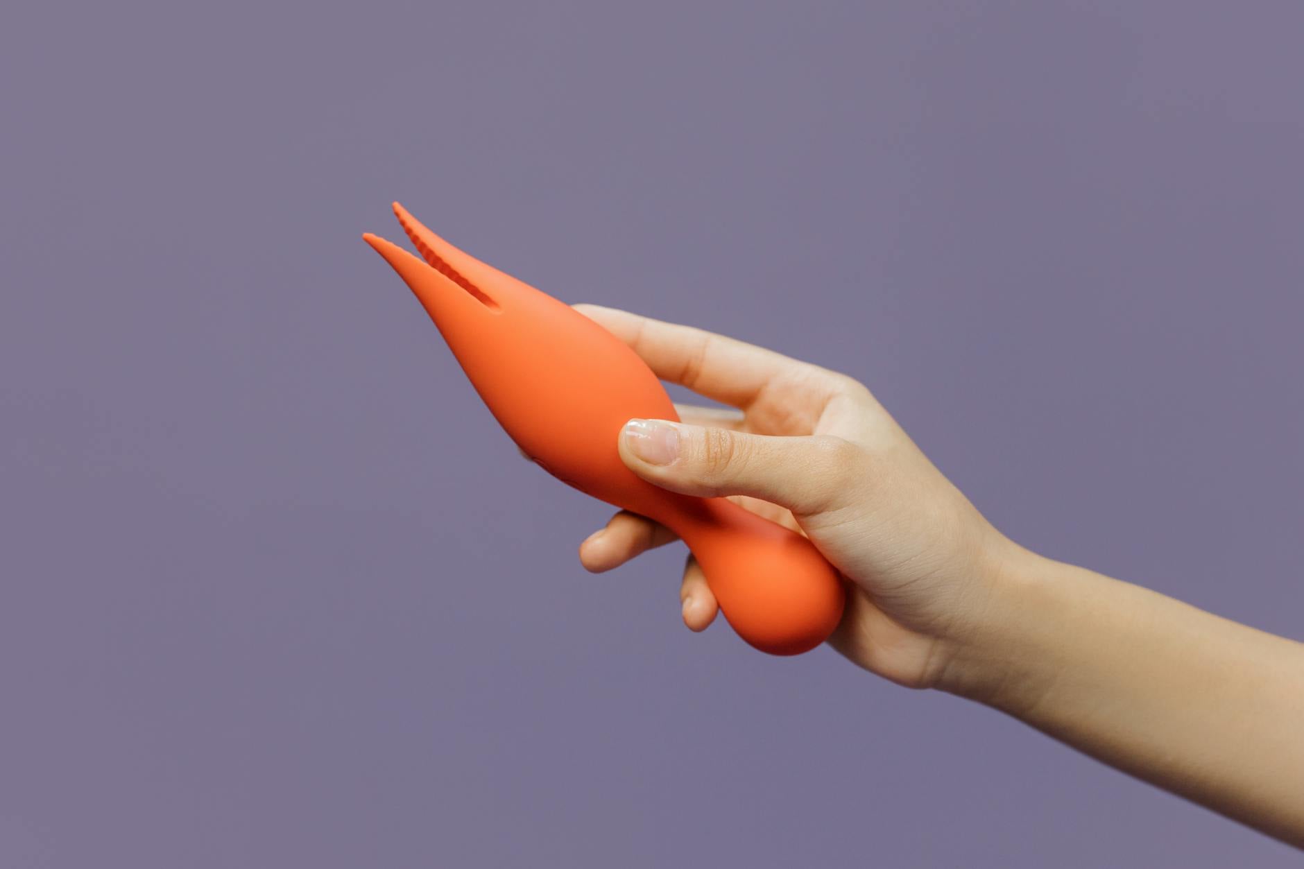 Close-up of a hand holding a vibrator against a minimalistic backdrop, representing modern self-care and personal intimacy.